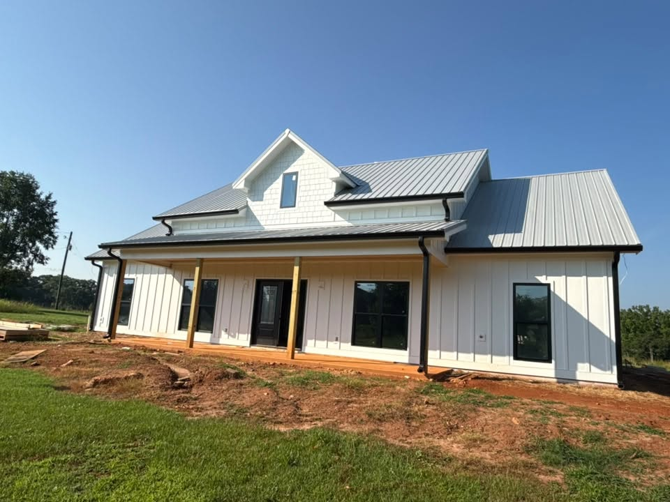 Newly installed seamless gutters on a white farmhouse